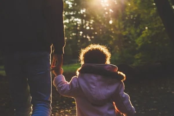 Adult holding the hand of a child walking outside