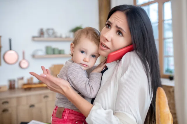 worried mom as she is on the phone with her childcare that can't watch her child today